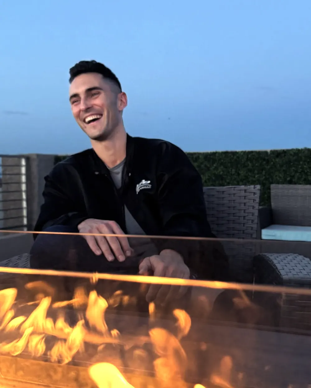 Jake Gallen laughing by a rooftop fire pit
